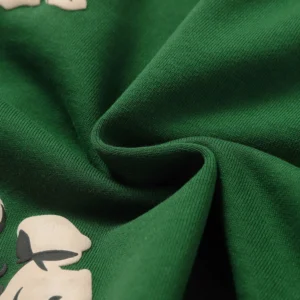 Close-up of green fabric showcasing foam flocking print design, highlighting the texture and quality associated with Denim Tears Cotton Flowers shorts.