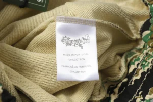 Label of DENIM TEARS Cotton Flower shorts showing care instructions and material details, featuring a camouflage pattern.