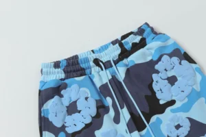 Denim Tears Cotton Flower shorts featuring a camouflage design in blue tones, showcasing elastic waistband and floral motifs, aligned with luxury replica clothing offerings.