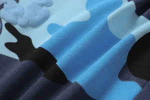 Camo pattern fabric featuring shades of blue, black, and light gray, highlighting the texture and design of Denim Tears Cotton Flower shorts.