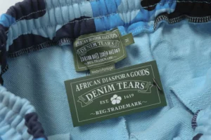 Denim Tears Cotton Flower shorts interior label featuring "African Diaspora Goods" and brand logo, showcasing quality craftsmanship and design details.