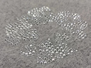 No brand or product type visible, close-up of silver rhinestones on grey fabric forming a patterned design accessory