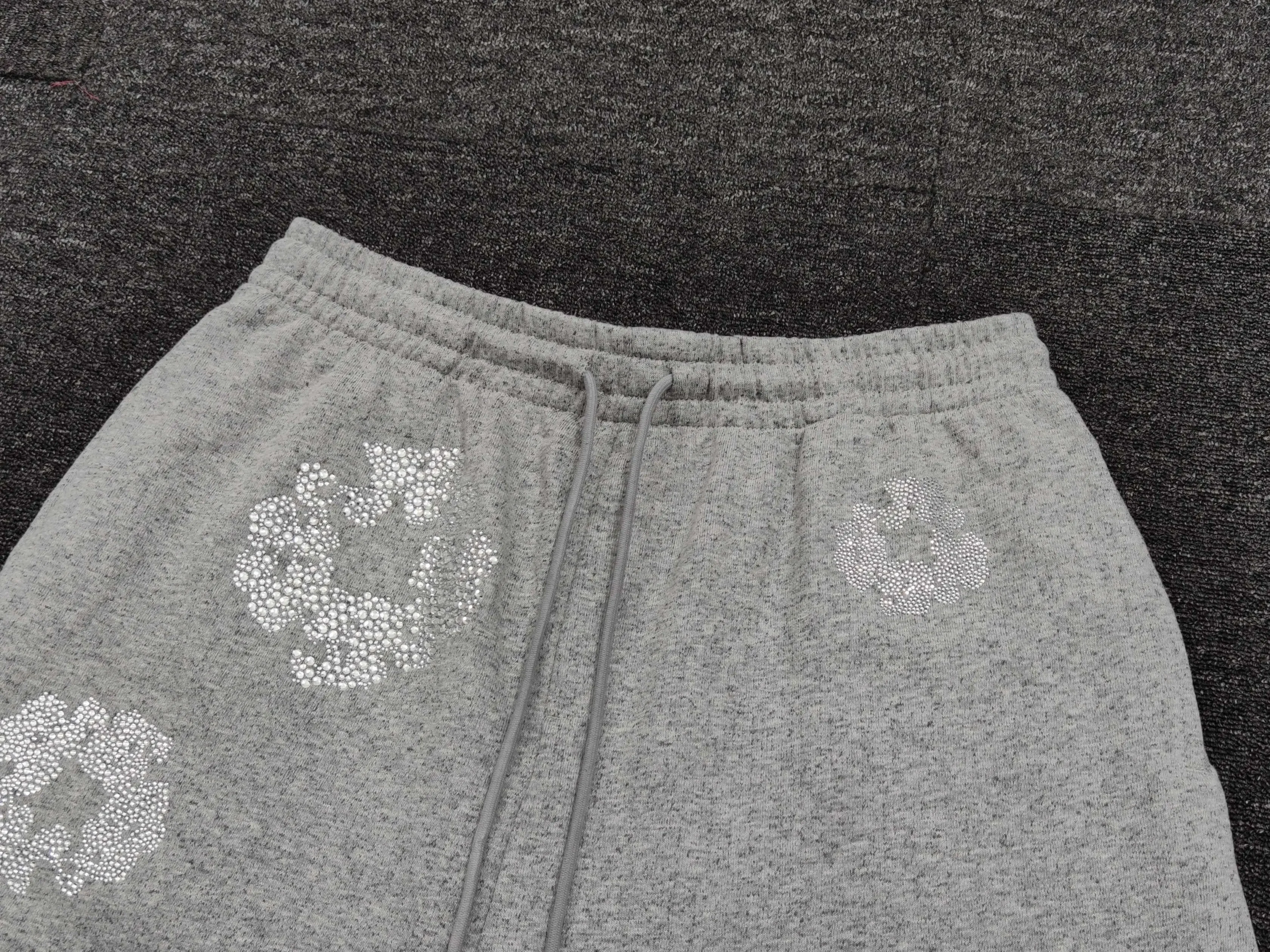 No brand or model information visible on gray sweatpants with white floral patterns and drawstring waistband