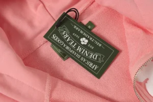 DENIM TEARS hoodie in pink with brand tag showcasing eco-friendly design and high-quality fabric.