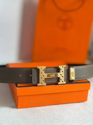 Hermes belt grey leather gold tone engraved H buckle accessory with branded keeper and orange box background
