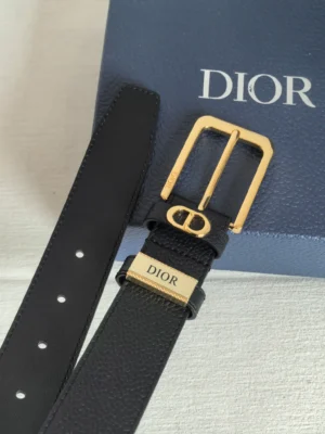 Dior unisex CD logo leather belt featuring a gold buckle and engraved logo, displayed against a blue Dior box, highlighting luxury fashion accessory design.