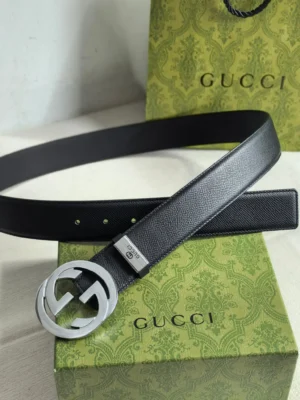 Gucci men's leather belt featuring a double G logo buckle, displayed on a green Gucci box, showcasing luxury craftsmanship and brand recognition.