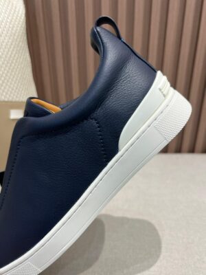 Minimalist navy leather slip-on shoes with a white rubber sole, showcasing a sleek design and premium craftsmanship, suitable for casual and smart-casual wear.