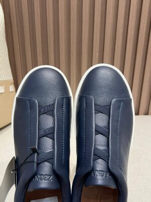 Minimalist navy leather slip-on shoes by Zegna featuring a clean design, elastic hidden panel, and lightweight rubber sole, ideal for comfort and style.