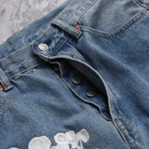 DENIM TEARS Water Washed Embroidery Vintage jeans featuring a close-up of the button fly and embroidered details on denim fabric.