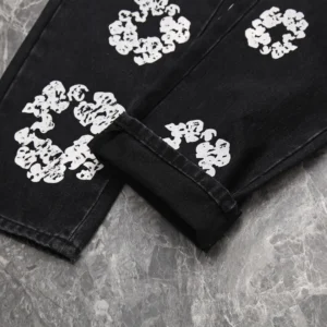 No brand or model information visible; detailed close-up of black denim pants with white distressed floral prints on fabric.