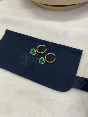 Apm Monaco Peacock Stone Love Circle Earrings displayed on a navy pouch with logo, featuring green heart stones and gold accents.