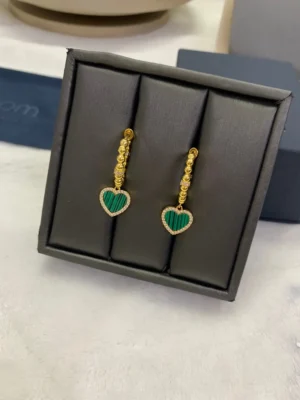 Apm Monaco Peacock Stone Love Circle Earrings displayed in a black jewelry box, featuring gold accents and green heart-shaped stones.