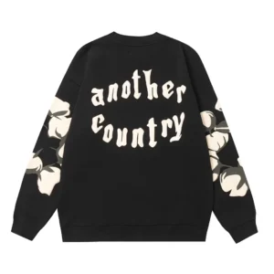 Black hoodie featuring "another country" text and floral designs on sleeves, representing Denim Tears trendy clothing collection.