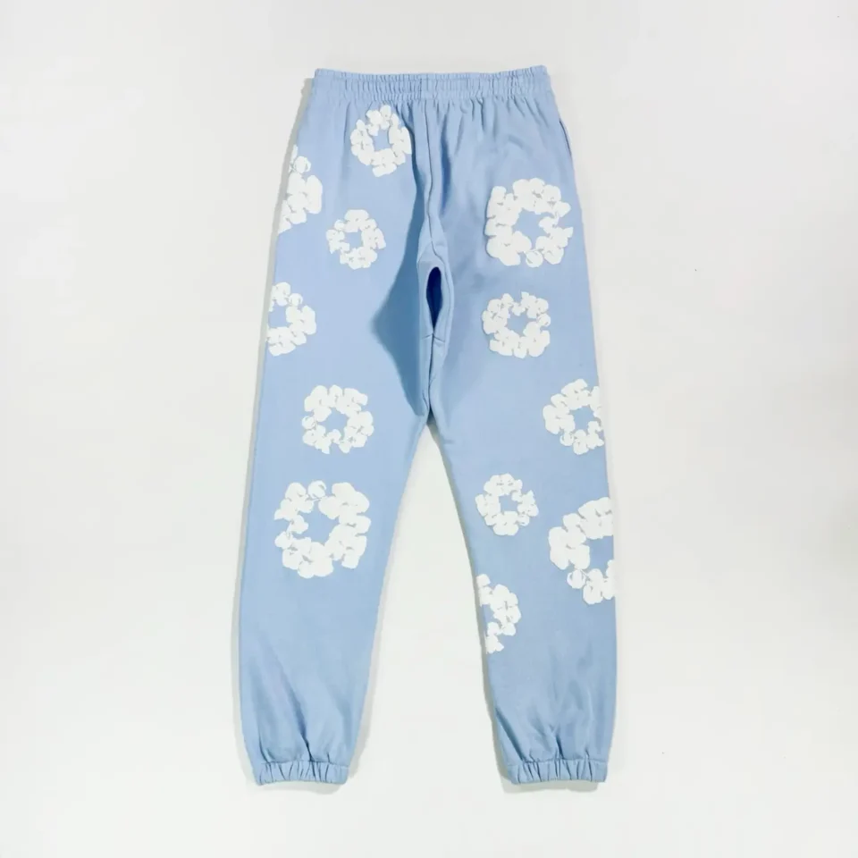 No brand visible, but based on structure: Light blue sweatpants with white floral print, elastic waist and cuffs, cotton material