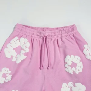 Pink cotton shorts featuring white cherry blossom designs, showcasing a comfortable elastic waistband and drawstring, part of the Denim Tears Mono Cherry Blossoms collection.