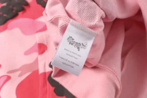 Denim Tears clothing tag white cotton label made in Portugal on pink camo fabric
