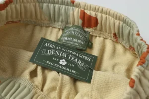 Denim Tears branded label on camo-patterned cotton sweatpants, showcasing high-quality materials and craftsmanship.