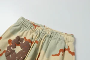 Foam flocking camouflage printed looped sweatpants from Denim Tears, featuring an elastic waistband and abstract design in beige and orange hues.