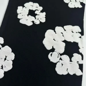 Unknown brand black fabric with white textured floral pattern textile material