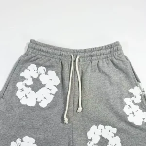 Grey cotton pants featuring white floral prints and drawstring waist, part of the Denim Tears Main Line collection.