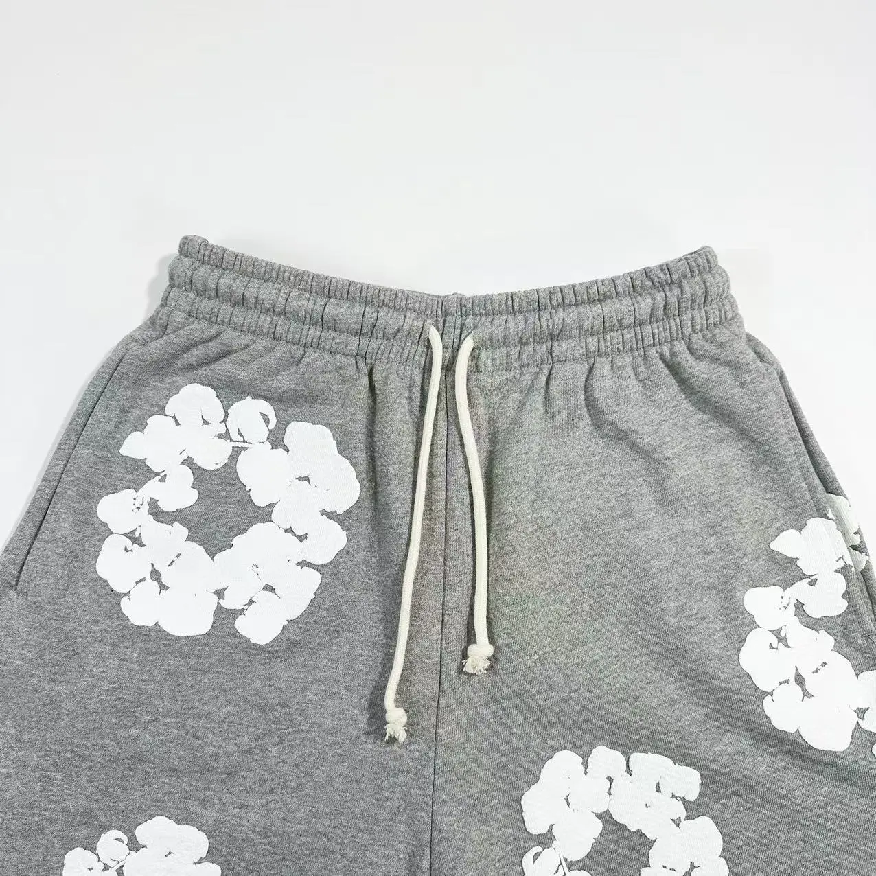 Grey cotton pants featuring white floral prints and drawstring waist, part of Denim Tears Main Line collection.