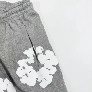 Grey cotton pants featuring white floral prints, part of the Denim Tears Main Line Hemp collection, emphasizing unique fabric texture and design.