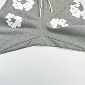 Grey cotton pants featuring white floral designs, showcasing the unique fabric texture and style of Denim Tears Main Line Hemp collection.