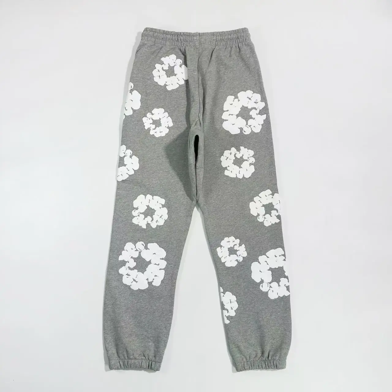 Grey cotton pants featuring white floral patterns, part of the Denim Tears Main Line collection, showcasing a relaxed fit and elastic waistband.