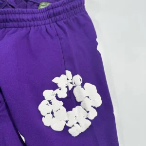 Purple sweatpants featuring a white kapok flower design, part of the Denim Tears mainline collection.