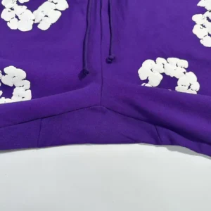 Denim Tears mainline purple sweatpants featuring white kapok flower designs and drawstring detail.