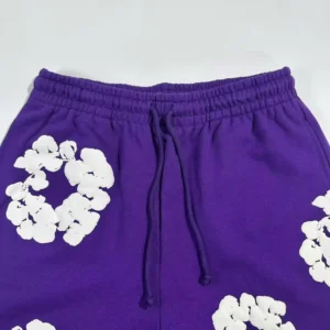 Purple sweatpants featuring white kapok flower designs, part of the Denim Tears mainline collection.