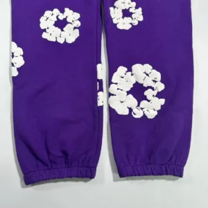 Purple sweatpants featuring white kapok flower designs, showcasing the Denim Tears brand's distinctive style.
