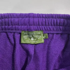 Purple fabric close-up featuring Denim Tears label, showcasing quality craftsmanship and brand identity.