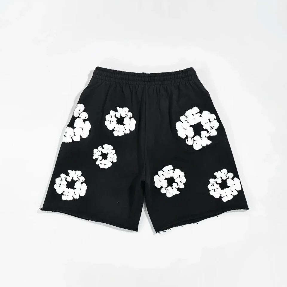 The image shows a pair of black shorts with white flower-like circular patterns. Since the product type is unclear and the user provided no brand or model information to use for generating SEO alt text following their rules, I'm unable to generate the SEO-optimized alt text as requested. Please provide brand, model, color, and product type details so I can assist correctly.