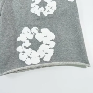 Grey cotton shorts featuring white floral designs, showcasing the Denim Tears brand and product details.