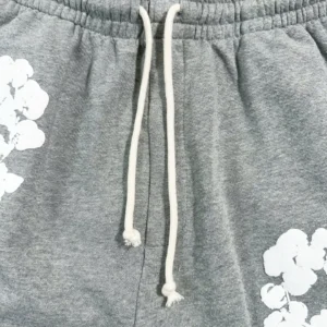 Grey cotton shorts featuring white floral designs and an adjustable drawstring, part of Denim Tears Main Line Hemp collection.