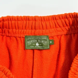 Denim Tears mainline orange kapok flower shorts waistband featuring brand label and textured fabric.