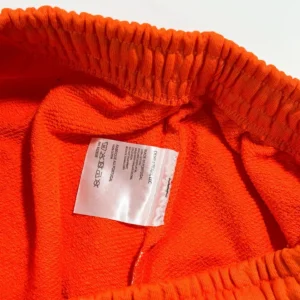 Close-up of the interior of Denim Tears mainline orange kapok flower shorts, showcasing the vibrant orange fabric and care label details.