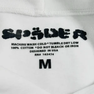 Sder label on a white hoodie displaying care instructions and size M, emphasizing premium craftsmanship and design.