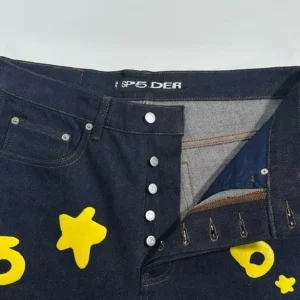 Sp5der Beluga Star Original Color Jeans featuring yellow star designs and button fly closure, highlighting unique denim fabric and style details.