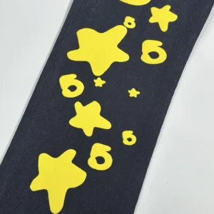 Yellow star and number designs on dark denim fabric, featured in Sp5der Beluga Star Original Color Jeans.