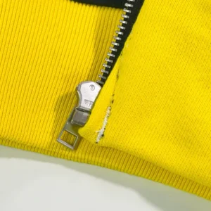 Close-up of yellow ribbed fabric featuring a silver zipper, showcasing the Sp5der TF Black and Yellow Riveted Zipper Shirt 08 design details.