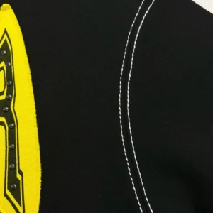 Black and yellow Sp5der TF shirt featuring riveted zipper details and contrasting stitching, showcasing high-quality fabric and design elements.