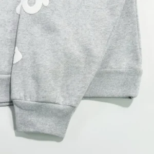 Light grey hoodie sleeve detail featuring ribbed cuff and white logo design, part of the Sder Light Grey Beluga Hoodie by SP5DER, emphasizing fabric quality and style.