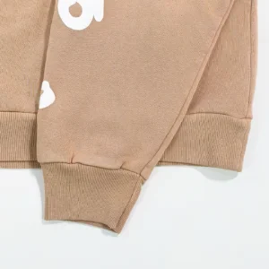 Close-up of Sder Camel Beluga Hoodie 05 sleeve featuring ribbed cuff and white logo detail, showcasing high-quality cotton fleece fabric.