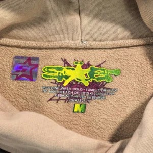 Sder Camel Beluga Hoodie 05 label featuring colorful logo and care instructions, highlighting SP5DER brand details.