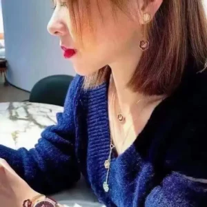 Chanel jewelry set gold color necklace and earrings with floral design on woman wearing blue sweater