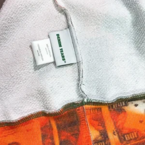 Denim Tears label on the interior of a brightly colored hoodie featuring a unique design, highlighting quality craftsmanship and brand identity.