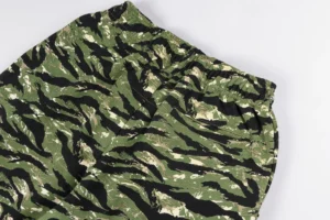 Sp5der 555555 Retro Camo Pink pants featuring a camouflaged design with green and black patterns, showcasing the fabric texture and waistband.